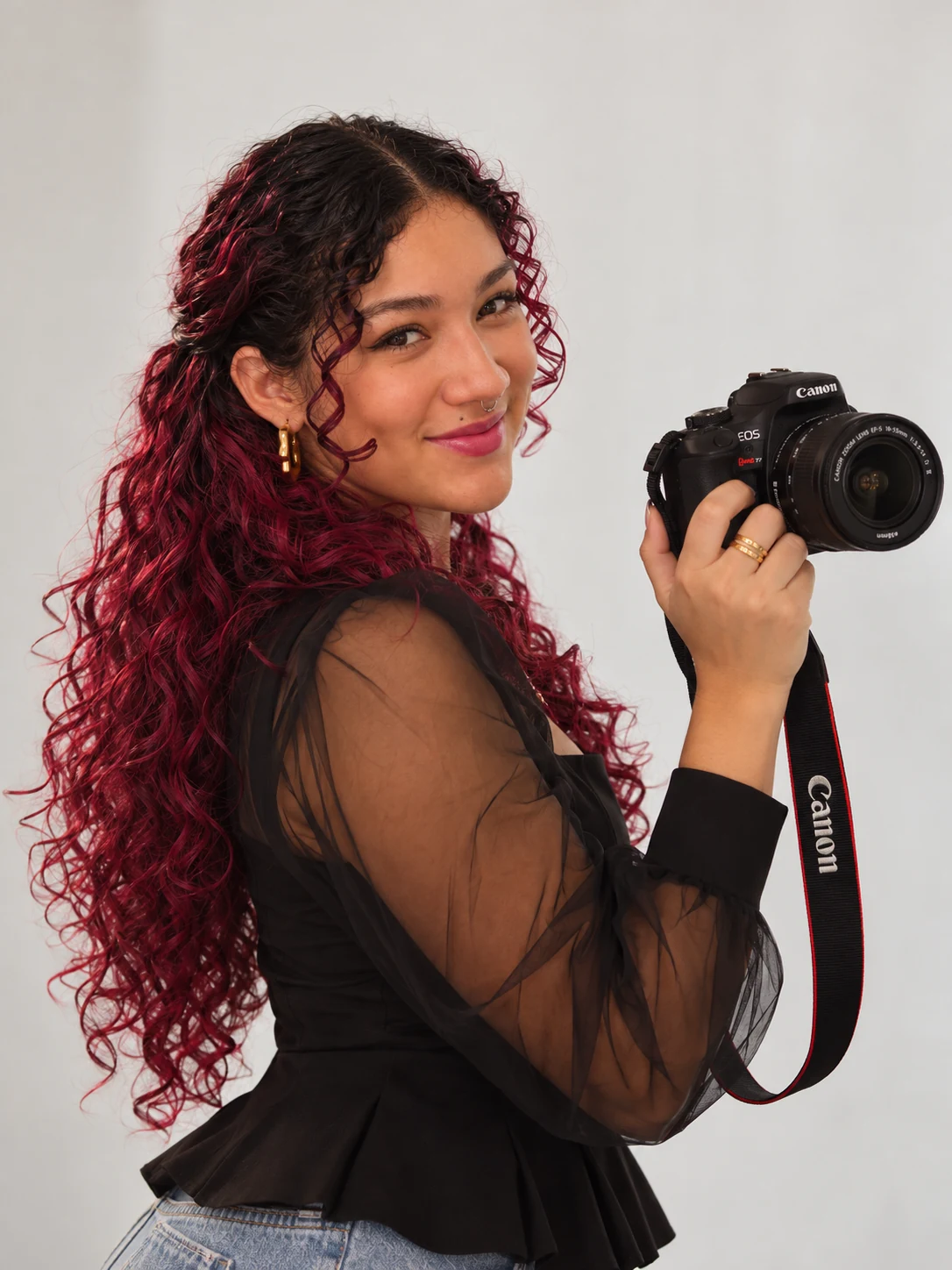 Elen Silva sorrindo, segurando a sua câmera Canon